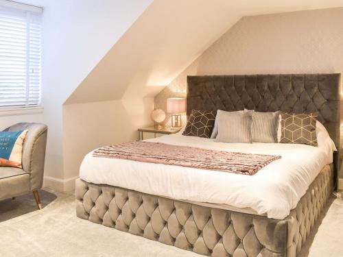 a bedroom with a large bed and a chair at Baileyfield Cottage in Edinburgh