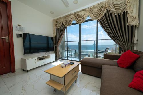 a living room with a couch and a large window at White Beach Holiday in Hulhumale