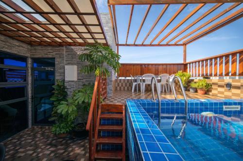 a patio with a swimming pool and a deck with a house at White Beach Holiday in Hulhumale