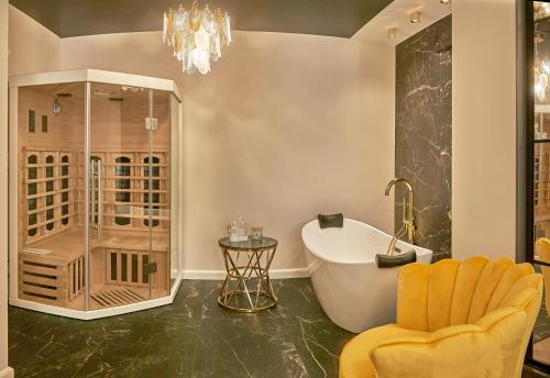 La salle de bains est pourvue d'une baignoire et d'un lustre. dans l'établissement Apartament Primavera 3 MINI SPA Komfort dla grup biznesowych , rodzin ,osób indywidualnych, à Kielce