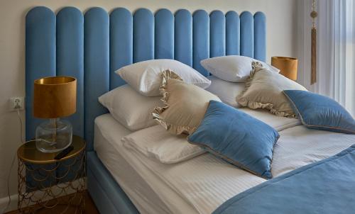 - un lit avec une tête de lit bleue et des oreillers dans l'établissement Apartament Primavera 3 MINI SPA Komfort dla grup biznesowych , rodzin ,osób indywidualnych, à Kielce