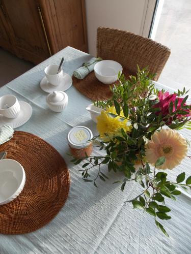 une table avec des assiettes et un vase de fleurs dans l'établissement Les coquetières, à Roz-sur-Couesnon