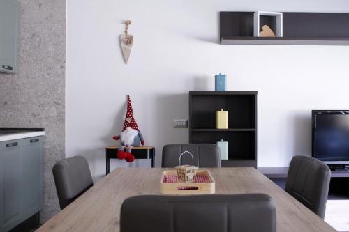 ein Wohnzimmer mit einem Tisch, Stühlen und einem TV in der Unterkunft IL CERVO - Dolomiti Affitti in Cavalese