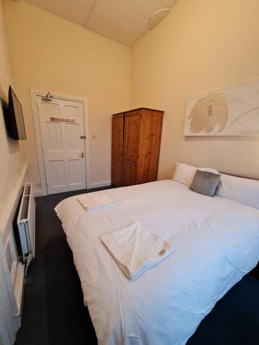a bedroom with a large white bed with a wooden cabinet at Pilrig St Rooms in Edinburgh