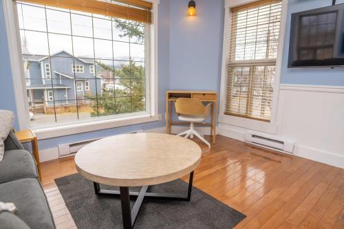 a living room with a table and two windows at Downtown Whitehorse Apartment in Old Town in Whitehorse
