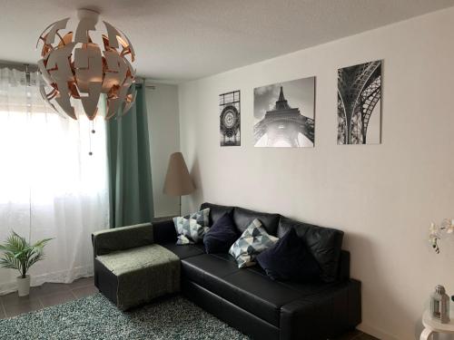 - un salon avec un canapé noir et un lustre dans l'établissement Superbe appartement neuf T3 de 71m2 en résidence a Marseille, à Marseille