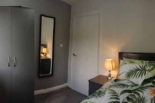 a bedroom with a bed with a mirror and a lamp at Cheerful 3 Bedroom Apartment in Nottingham