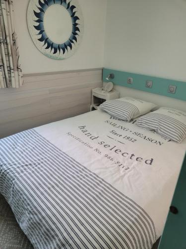 a bed with a white comforter and a mirror at Arzon rue de la Plage Résidence Bretagne Douce in Arzon