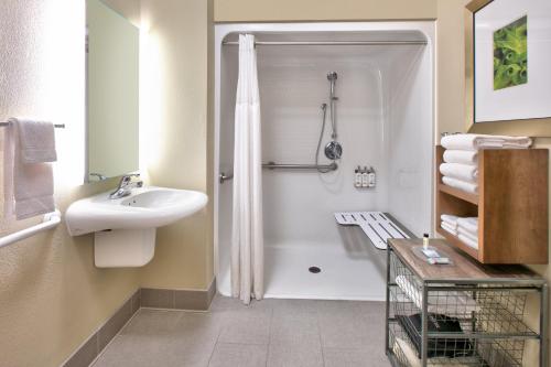 a white bathroom with a sink and a shower at Staybridge Suites Corning, an IHG Hotel in Corning