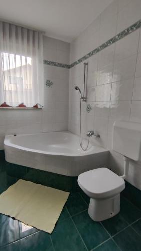 a white bathroom with a tub and a toilet at Apartma Alda in Preserje