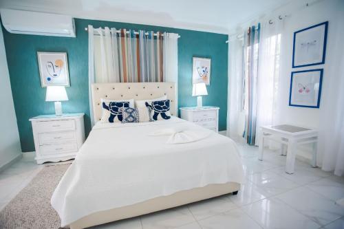 Paraíso的住宿－Villa impecable con piscina privada en Juan Dolio，卧室配有白色大床和蓝色的墙壁