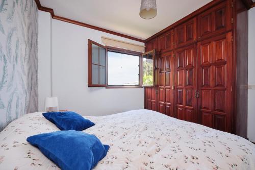a bedroom with a bed with blue pillows on it at La casita del puerto in Agaete