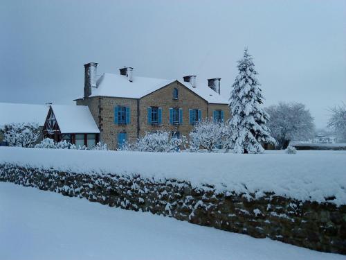 duży ceglany dom z pokrytym śniegiem dziedzińcem w obiekcie Les coquetières w mieście Roz-sur-Couesnon
