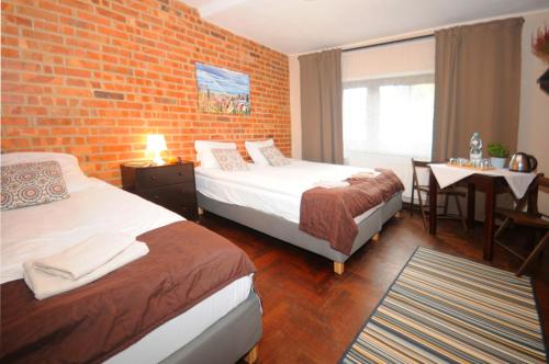 a hotel room with two beds and a brick wall at Centrum Turystyki Niekonwencjonalnej in Srebrna Góra