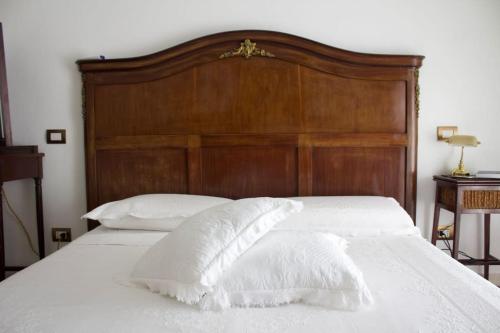 - un lit blanc avec une tête de lit en bois et des oreillers blancs dans l'établissement Lux Domus, à Bari