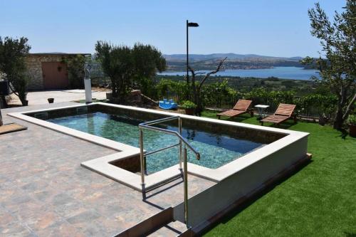 a swimming pool in a yard with two chairs at Villa Serenity in Šibenik