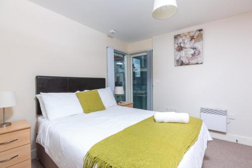 a bedroom with a large white bed with a yellow blanket at Marina View Apartment in Swansea