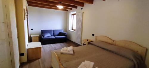 a bedroom with a bed and a blue couch at Agriturismo El Bocolar in Marano di Valpolicella