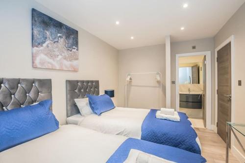 a bedroom with two beds with blue pillows at Langston House: 2 Bed, 2 Bath Luxury Apartment in Hedgerley