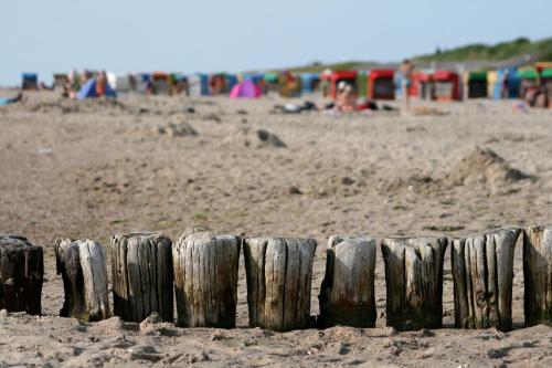 a wooden fence on a beach with people in the background at Gasthaus Knudsen in Utersum