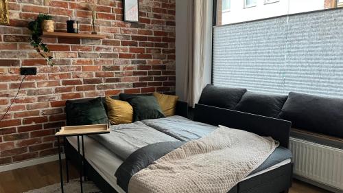 a bed in a room with a brick wall at Designwohnung Schaufenster sehr zentral gelegen in Hannover