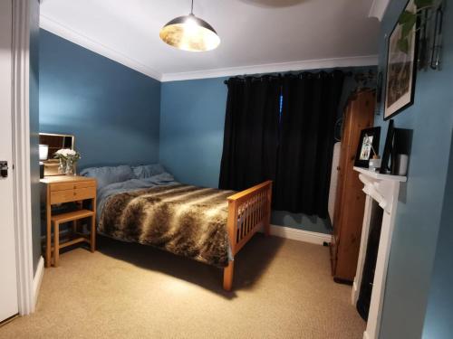 a bedroom with blue walls and a bed and a desk at Dragonfly Retreat Lowestoft Suffolk in Pakefield
