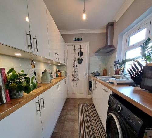 a kitchen with white cabinets and a black dishwasher at Dragonfly Retreat Lowestoft Suffolk in Pakefield