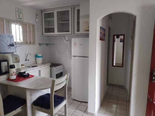 eine Küche mit einem Tisch und einem weißen Kühlschrank in der Unterkunft Condomínio Mar de Búzios in Nísia Floresta