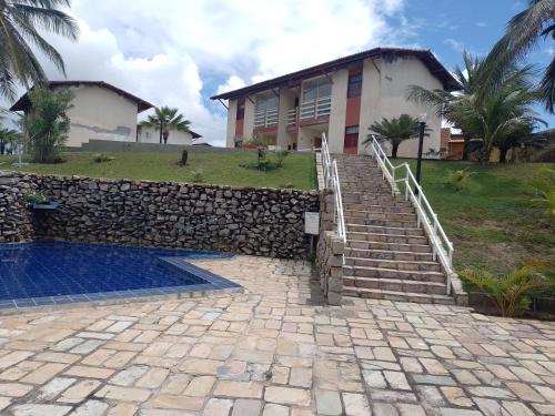 a house with a stone staircase leading to a swimming pool at Condomínio Mar de Búzios in Nísia Floresta