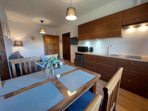 a kitchen with a table with a vase of flowers on it at Watra apartamenty z aneksami in Wetlina