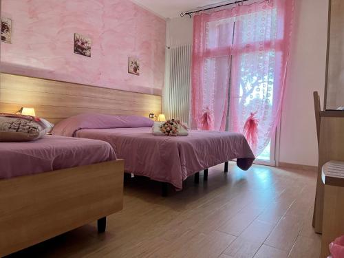 a pink room with two beds and a window at Agriturismo Le Essenze - Terrazza sulla Romagna in Cesena