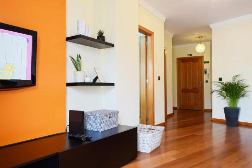 a living room with orange walls and wooden floors at Perola, a Home in Madeira in Funchal