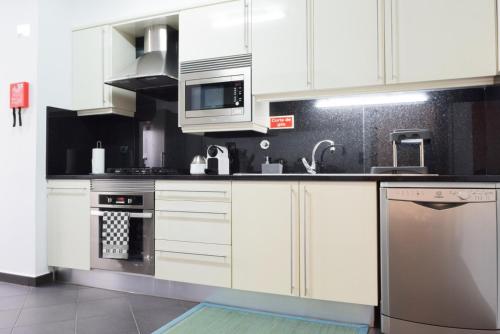 a kitchen with white cabinets and stainless steel appliances at Perola, a Home in Madeira in Funchal