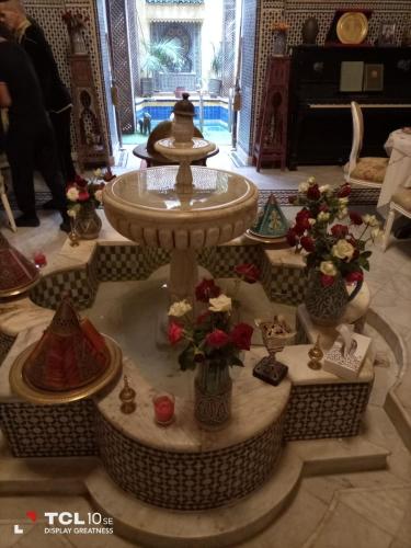 a fountain in the middle of a room with vases of flowers at Palais AL Firdaous in Fès