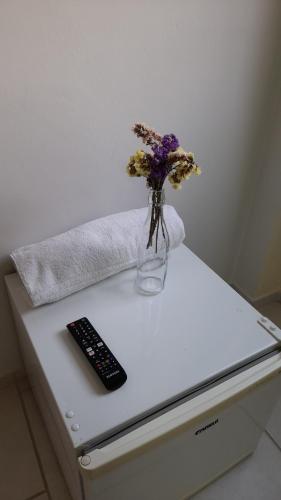 a vase of flowers and a remote control on a table at Casa Almeida in Salvador