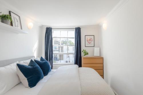 a white bed with blue pillows in a bedroom at The Dalston Maisonette in London