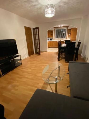 a living room with a glass table and a television at 3 bedroom home-inverkeithing in Fife