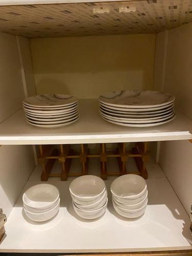 a stack of plates and bowls on a shelf at 3 bedroom home-inverkeithing in Fife