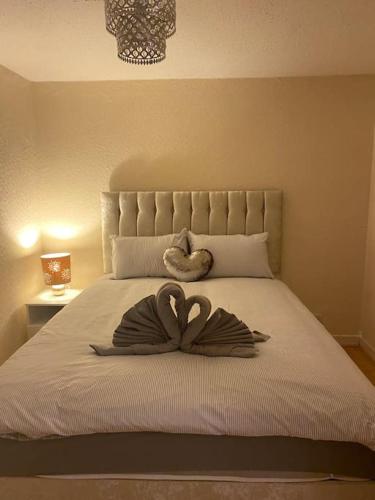een groot bed met een hartvormige handdoek erop bij 3 bedroom home-inverkeithing in Fife