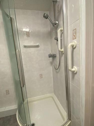 een douche met een glazen deur in de badkamer bij 3 bedroom home-inverkeithing in Fife