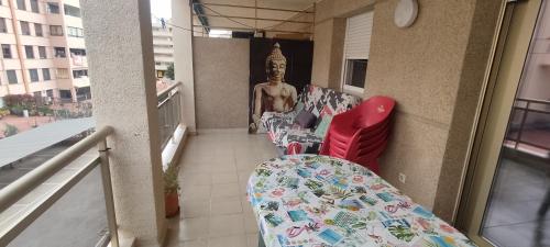 einen Balkon mit einem Tisch, Stühlen und einer Statue in der Unterkunft vacaciones en pineda con 2 piscinas, playa a 5 min in La Pineda