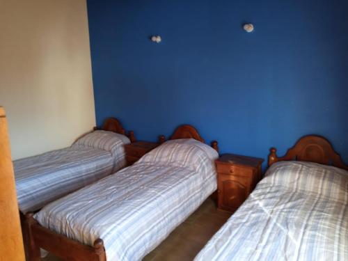 3 Betten in einem Zimmer mit blauen Wänden in der Unterkunft El Boulevard in Viedma