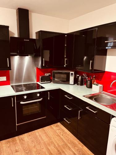 a kitchen with black and red cabinets and a sink at 'Woodbury' at stayBOOM in Lancaster