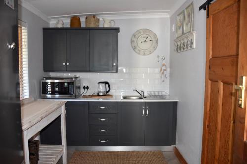 a kitchen with black cabinets and a clock on the wall at Luxury and homely stay in Oudtshoorn