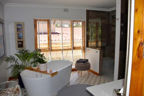 uma casa de banho com uma banheira e uma janela em Luxury and homely stay em Oudtshoorn