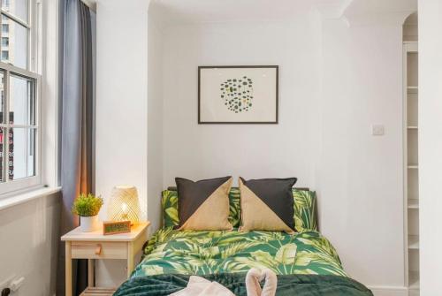 a bedroom with a green bed with pillows at Modern 2 bedroom apartment in the heart of London in London