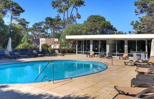 a swimming pool with chairs and a building at Torre Tressesenta Apto 1508 in Punta del Este