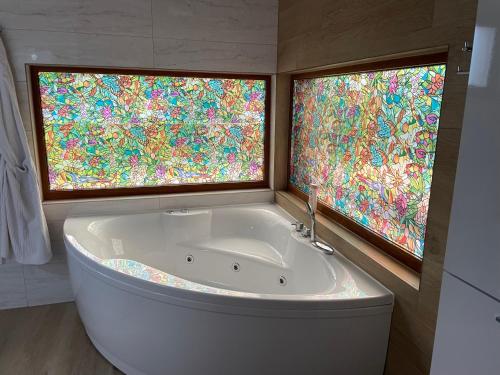 a bath tub in a bathroom with two windows at Josanica Bed&Breakfast in Konjic