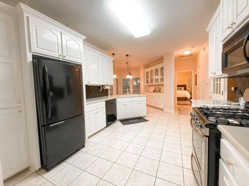 uma cozinha com um frigorífico preto e armários brancos em Spacious King Suite Mid Town Home With Serene Patio em Hattiesburg