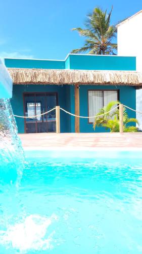 una casa azul con una palmera en el agua en Wind Village Chalés en São Miguel do Gostoso